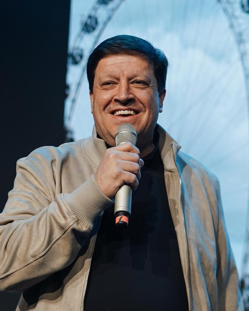 Pr. Jocymar Fonseca sorrindo com microfone no palco