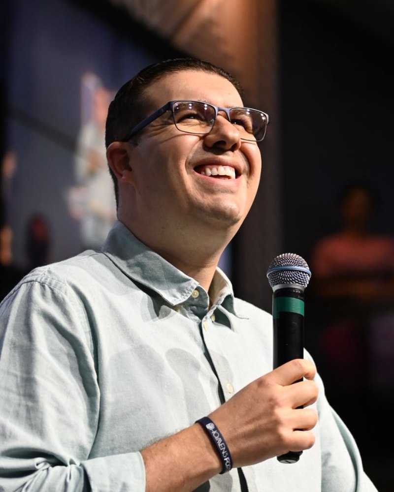 Pr. Geraldo Majella sorrindo no púlpito com microfone