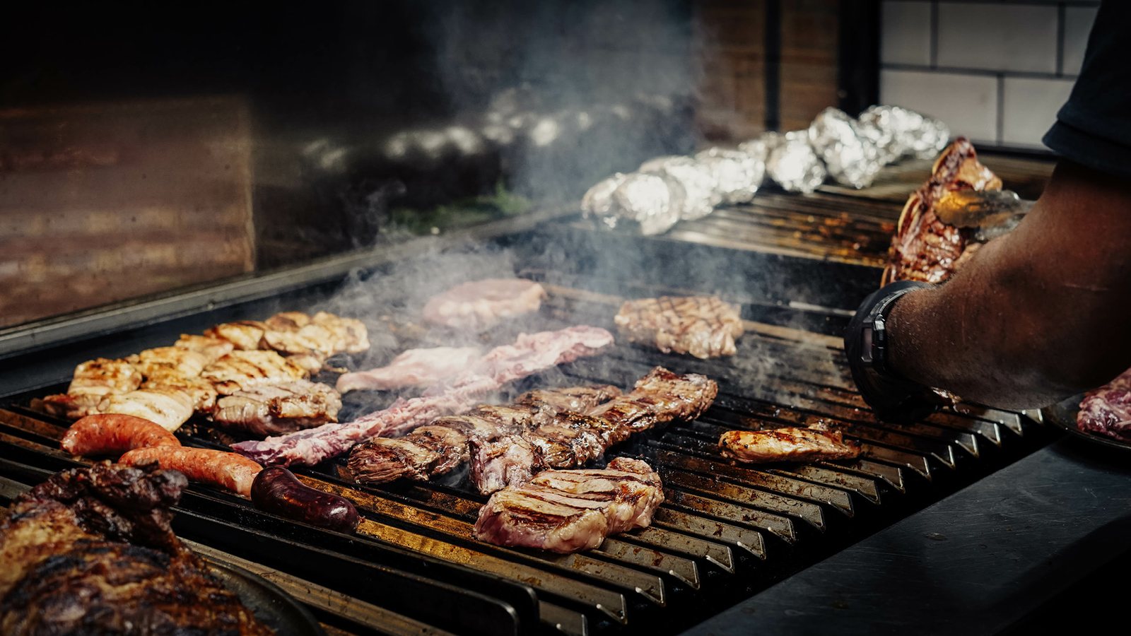 Carnes, linguiças e frango na grelha da parrilla com fumaça